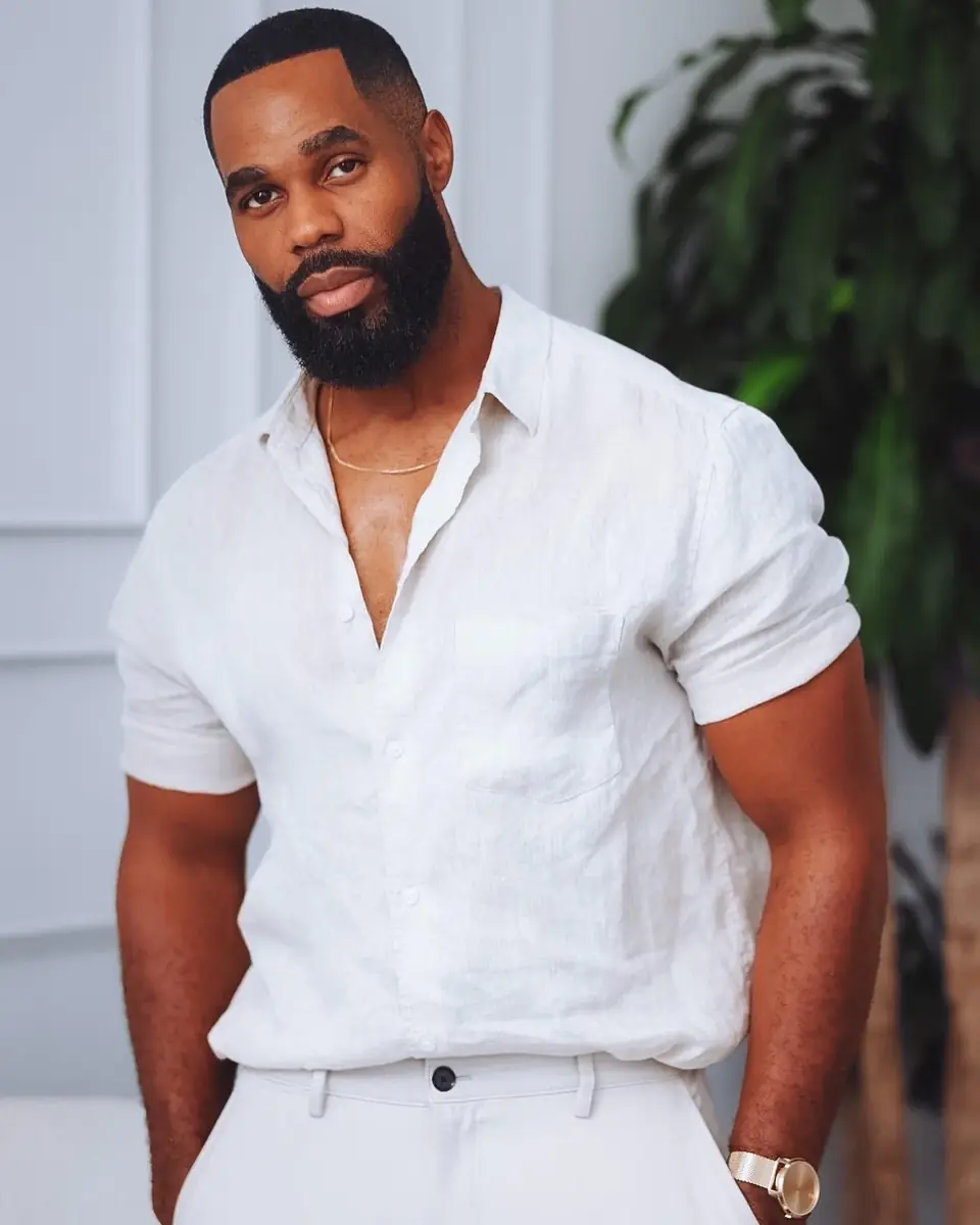 Portrait of Ezekiel Azonwu in a white linen shirt beside a green plant